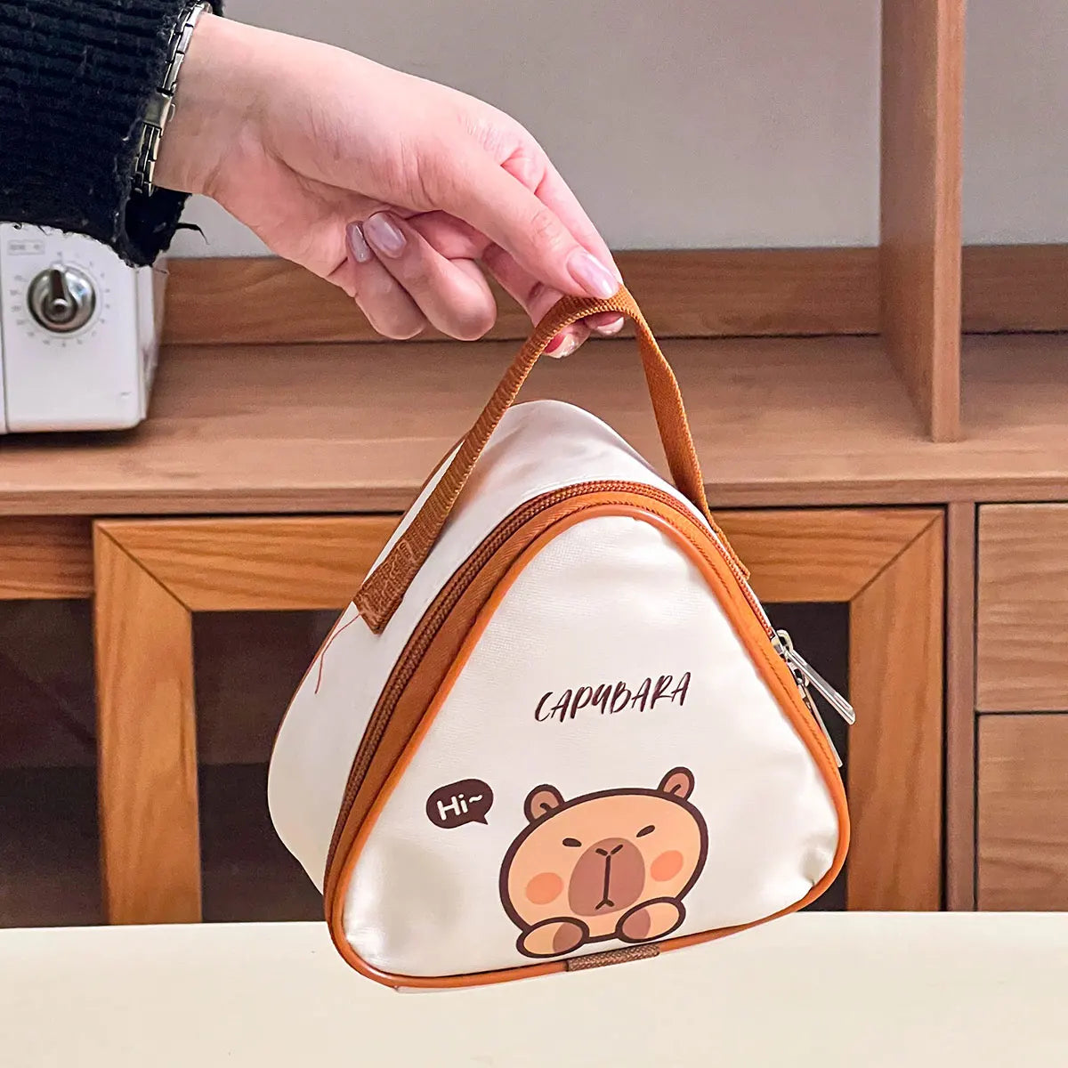 Small pouch with kawaii cartoon bear design held by a hand against a wooden background
