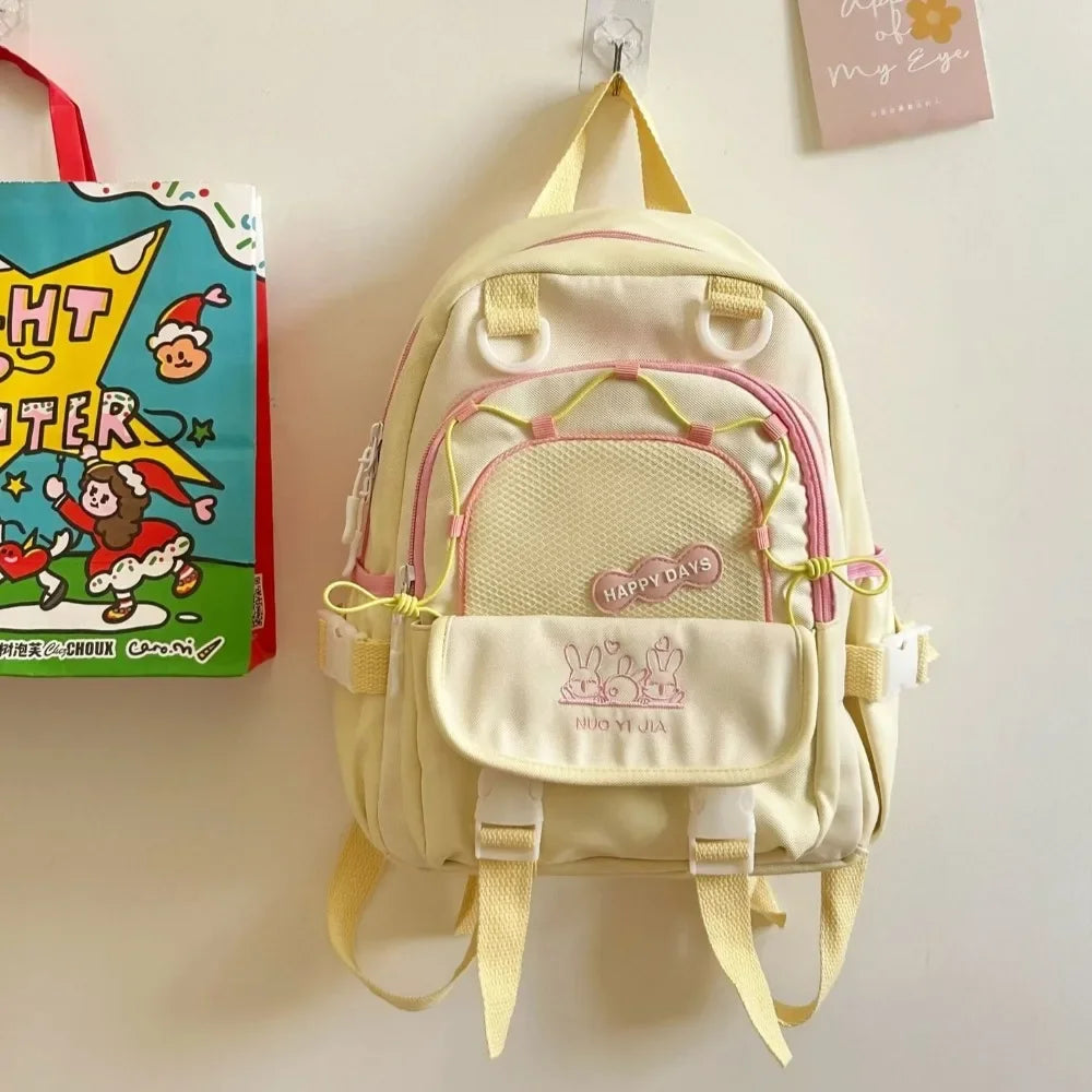 Light yellow Kawaii backpack with pink accents on a beige wall