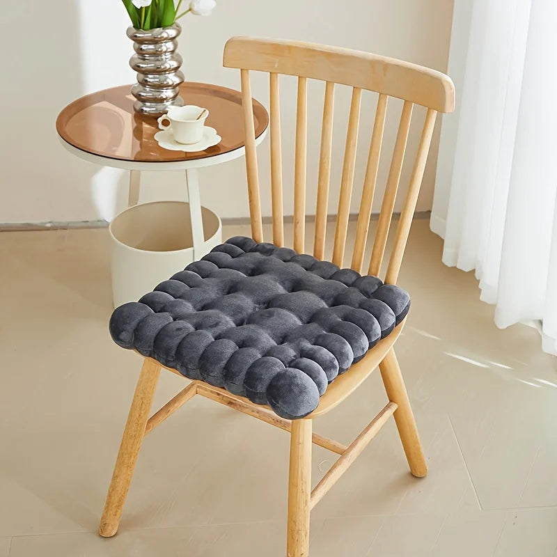 Gray kawaii cushion on a wooden chair with a small table and decor in the background
