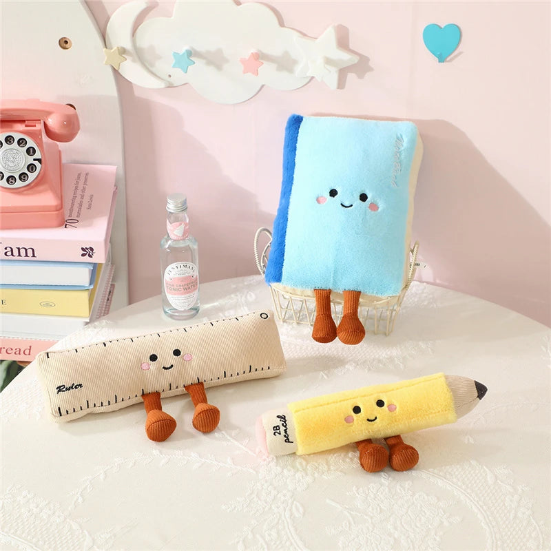 Kawaii plush toys shaped like a pencil, ruler, and bottle on a desk with a pink background.