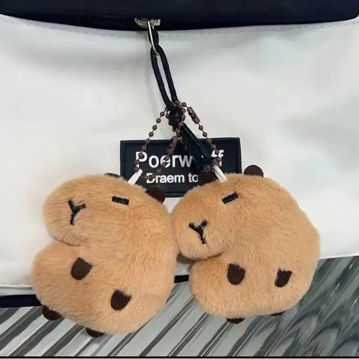Two kawaii fluffy brown bear-shaped keychains hanging from a black strap on a white background.
