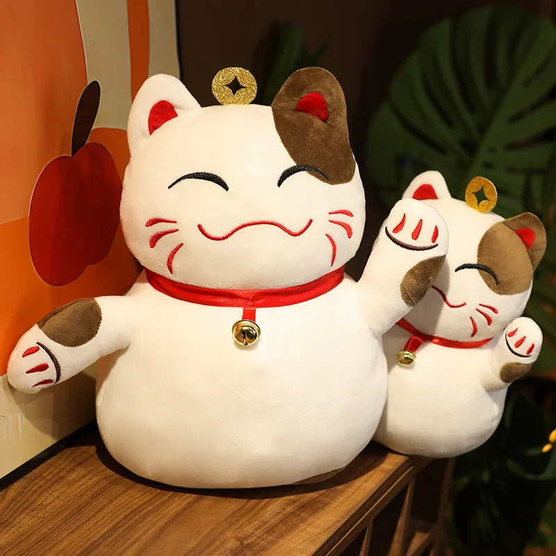 Two kawaii plush Maneki Neko cats on a wooden surface with a colorful background.