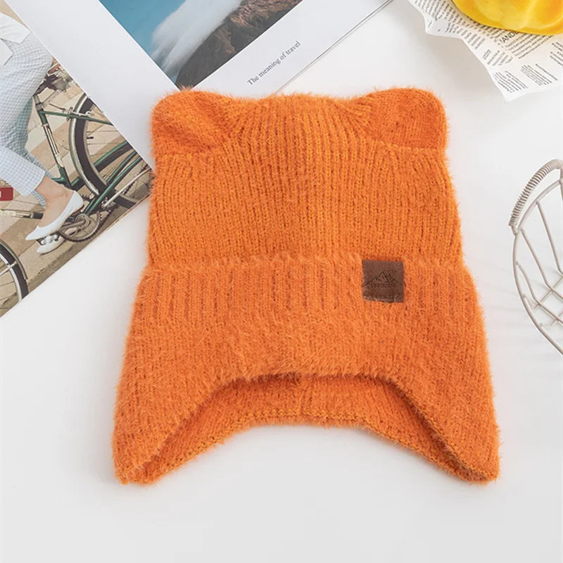 Orange knitted Kawaii beanie with a brown label on a white surface