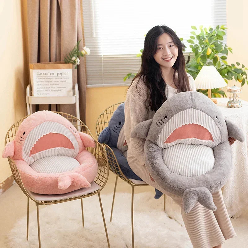 Woman holding a shark-shaped kawaii cushion in a home setting with another shark cushion on a chair.