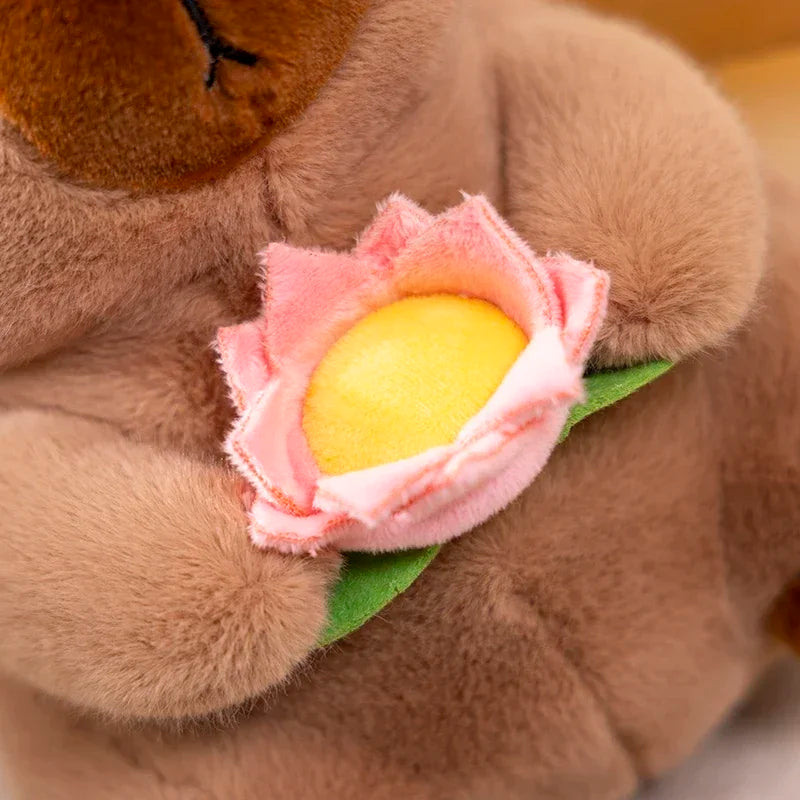 Kawaii plush teddy bear holding a pink flower with a yellow center.