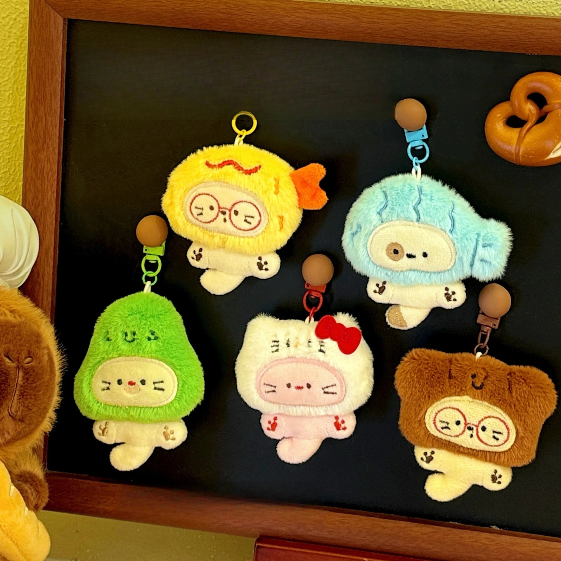 Set of plush keychains with kawaii cartoon designs on a dark surface.