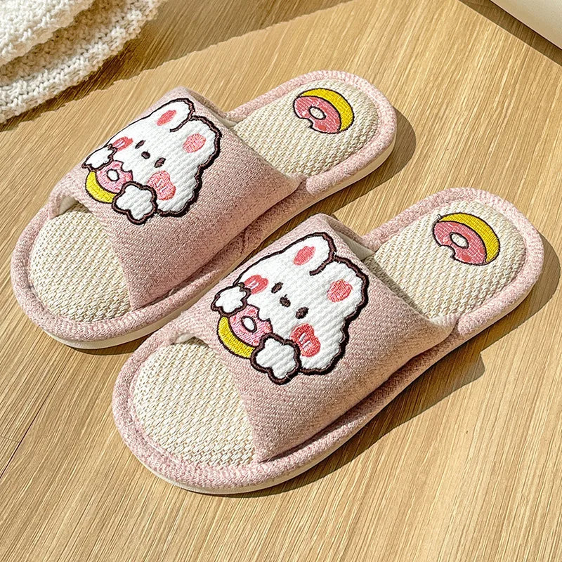 Pair of pink slippers with kawaii cartoon character design on a wooden surface