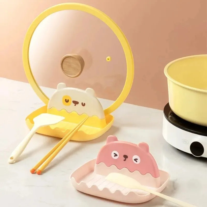 Cute ceramic bowls with kawaii animal faces, chopsticks, and a small electric stove on a light background