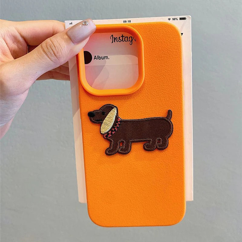Orange phone case with a kawaii dachshund design held by a hand against a gray background
