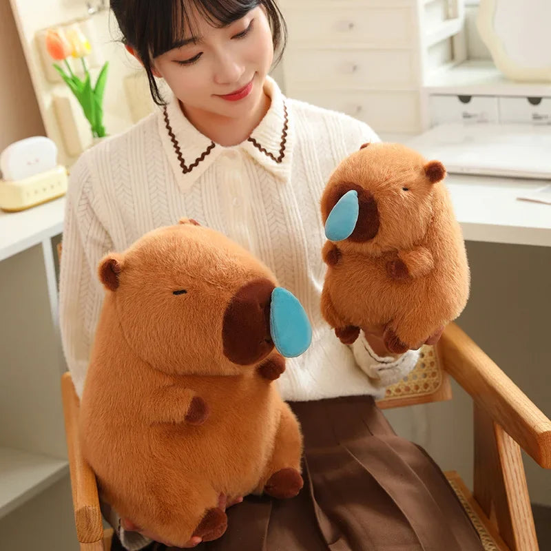Woman holding two kawaii plush beavers with blue tags in a home setting