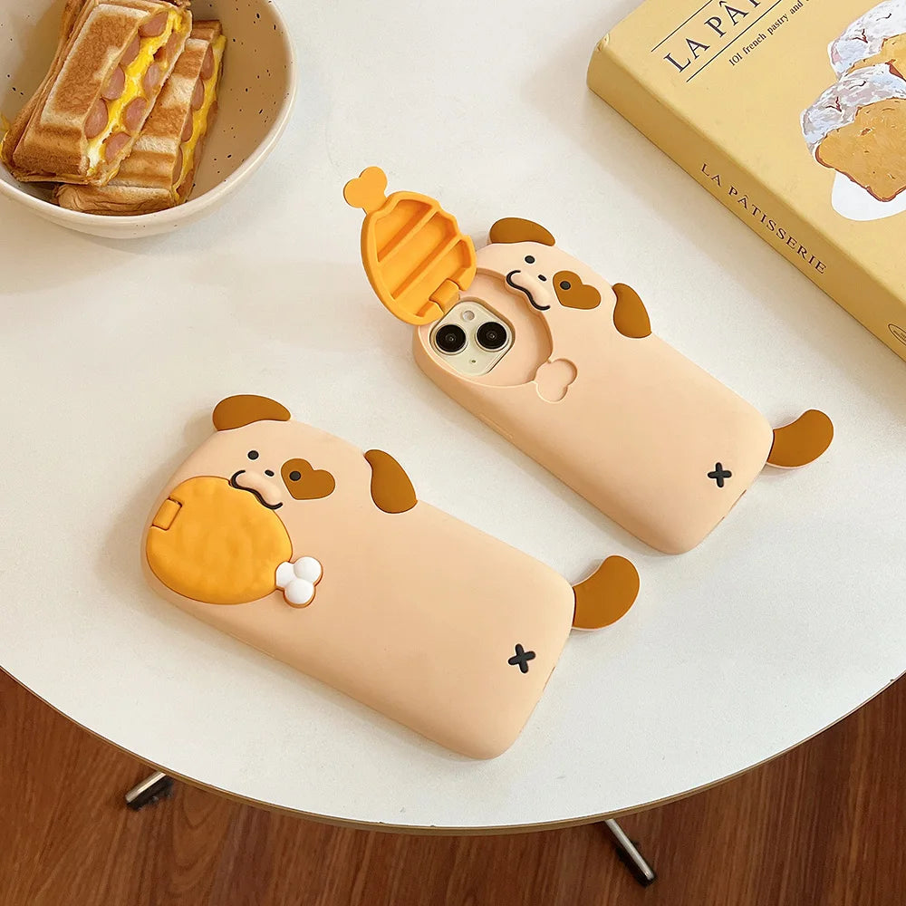 Two kawaii cartoon-style phone cases resembling dogs on a table with a book and food.