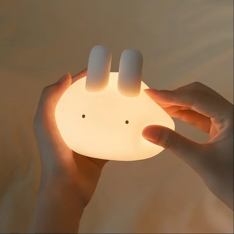 Person holding a round, rabbit-shaped kawaii night light with a warm glow.