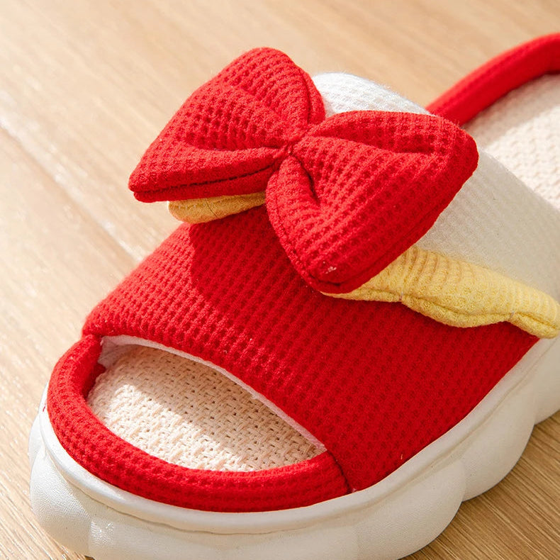 Red sandal with a large kawaii bow on a wooden surface