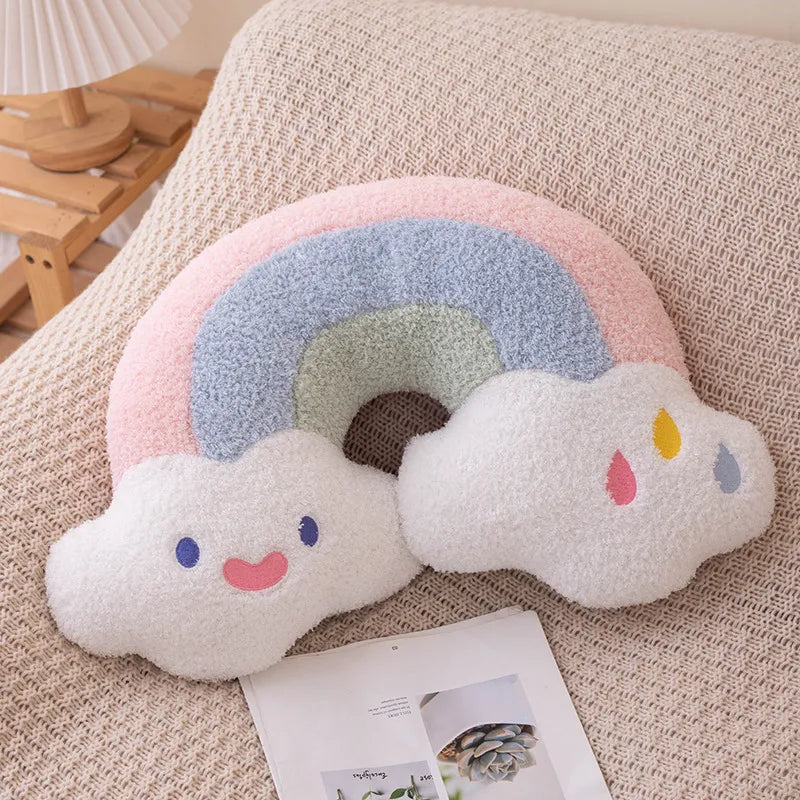 Kawaii plush rainbow-shaped pillow with a cloud face on a beige surface.
