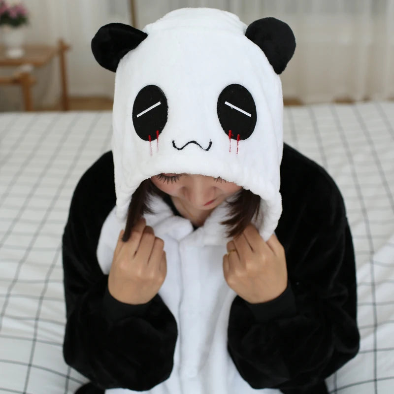 Person wearing a kawaii panda costume with a sad face design on a bed.