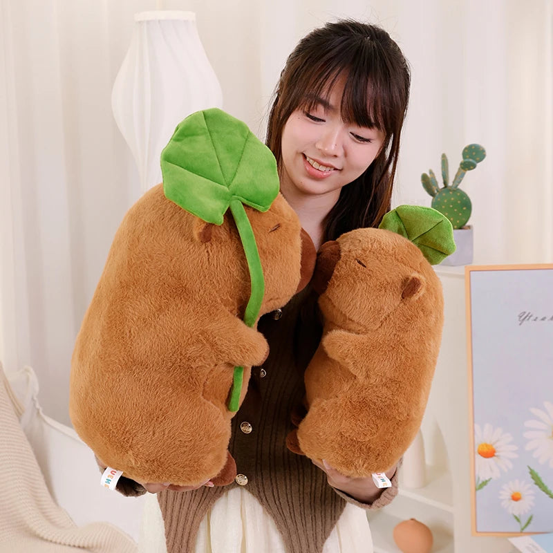Person holding a kawaii plush avocado toy in a room with a plant and decorative items.