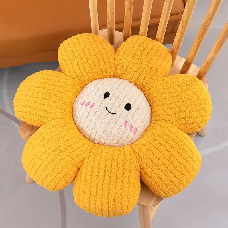 Yellow flower-shaped kawaii cushion with a smiling face on a wooden chair.