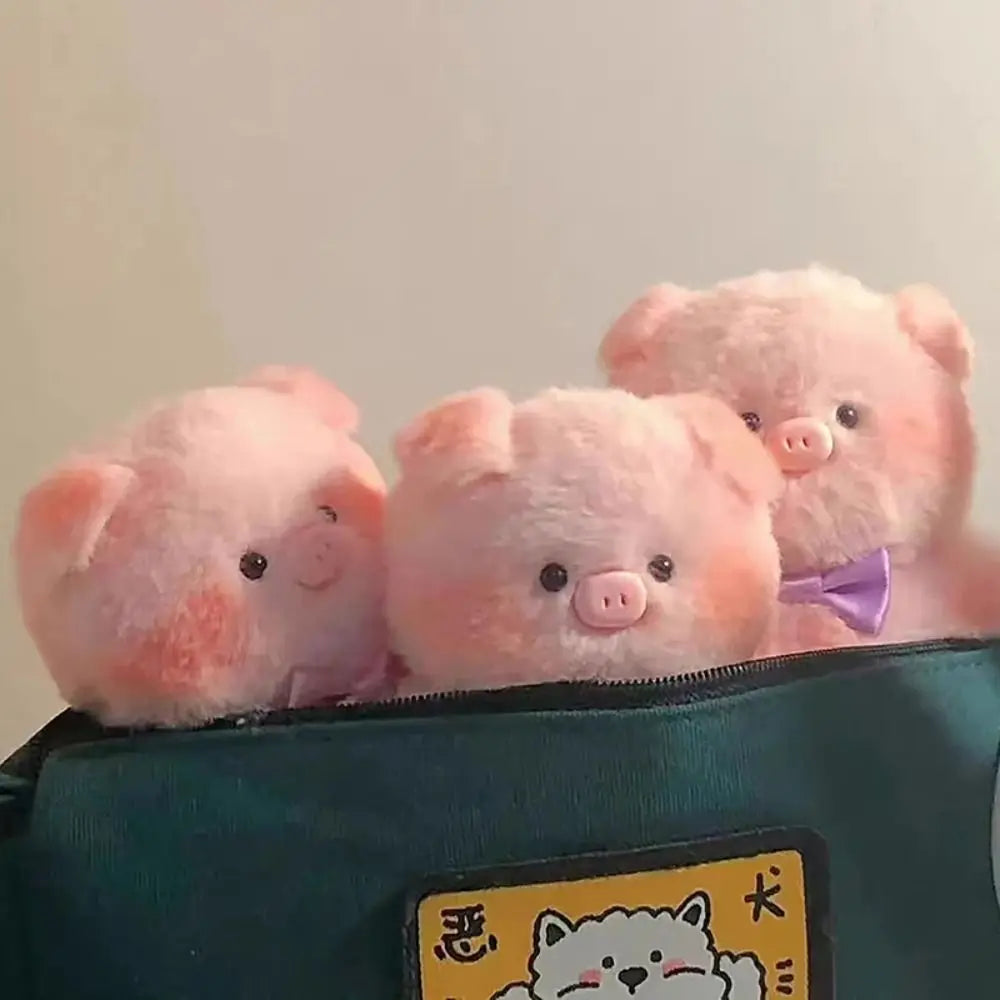Three pink plush pigs peeking out from a green bag with a kawaii cartoon character label.