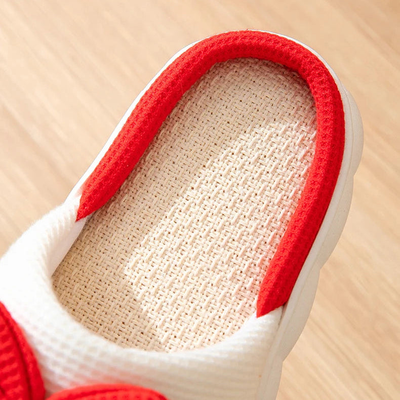 Close-up of a kawaii-style red and white shoe with textured sole on a wooden surface