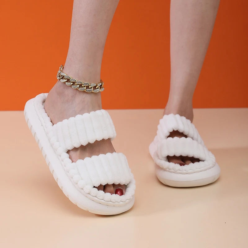 White fuzzy kawaii sandals worn with a gold chain bracelet on an orange and beige background