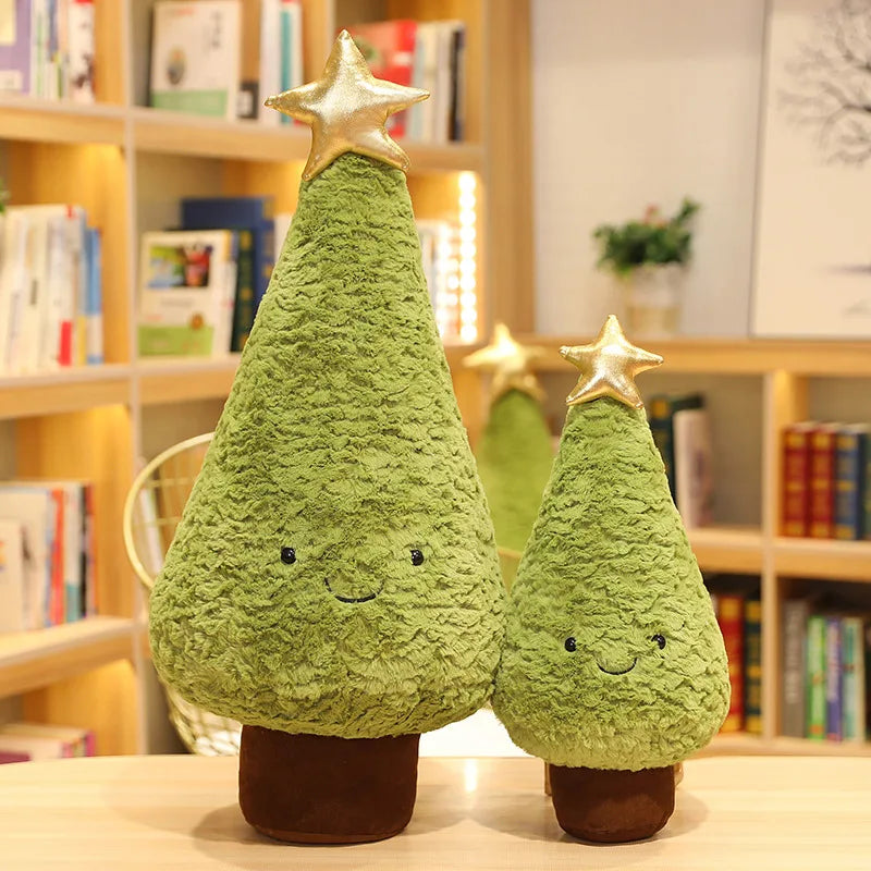 Two green kawaii plush Christmas trees with star toppers on a surface with bookshelves in the background.