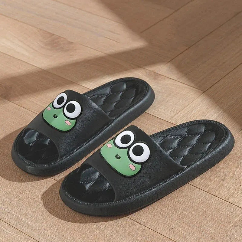 Black slippers with green kawaii frog faces on a wooden floor