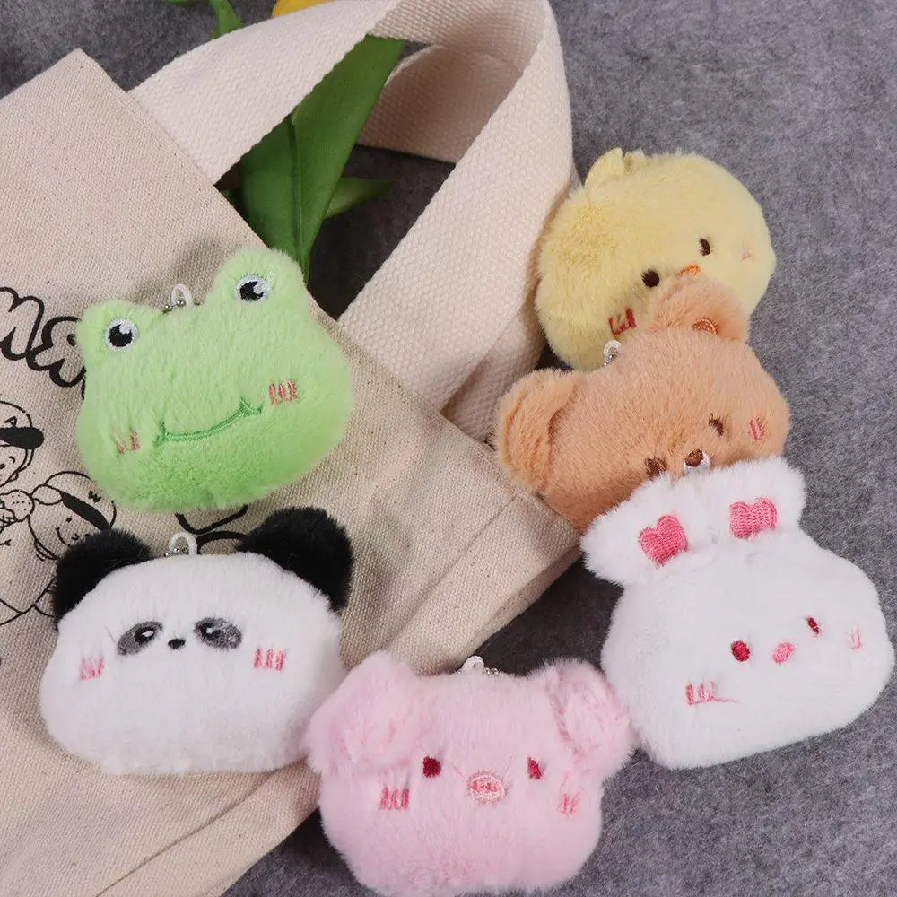 Set of small plush toys including a kawaii frog, chick, panda, and others on a textured surface.