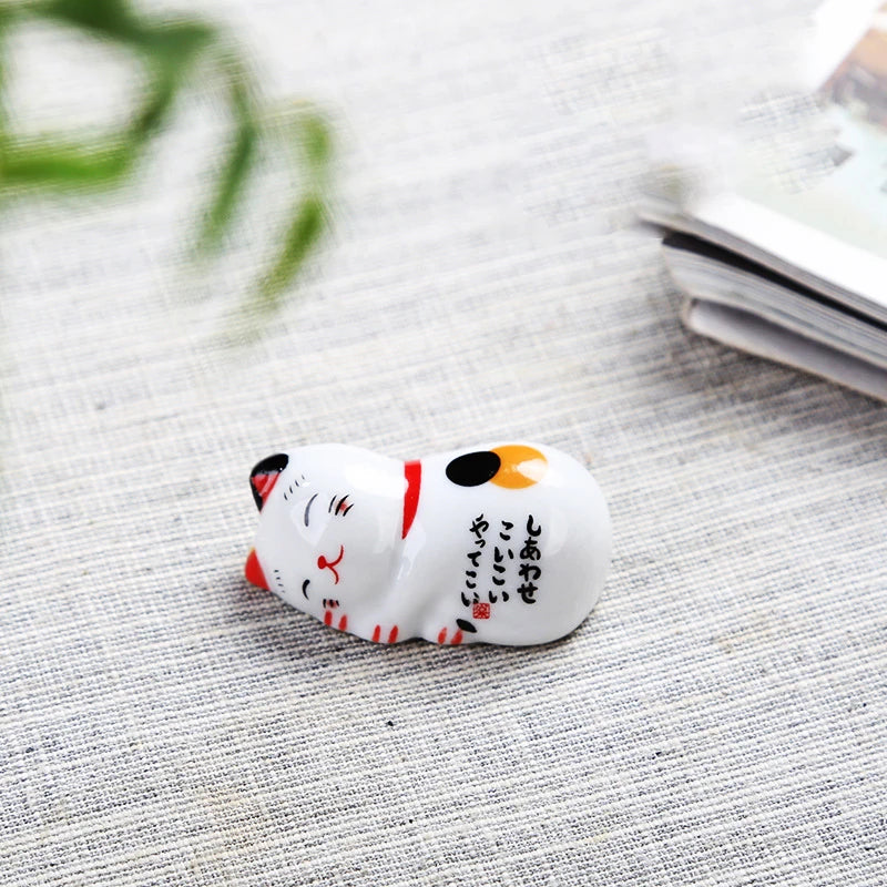 Small ceramic kawaii cat-shaped object with black text on a textured surface