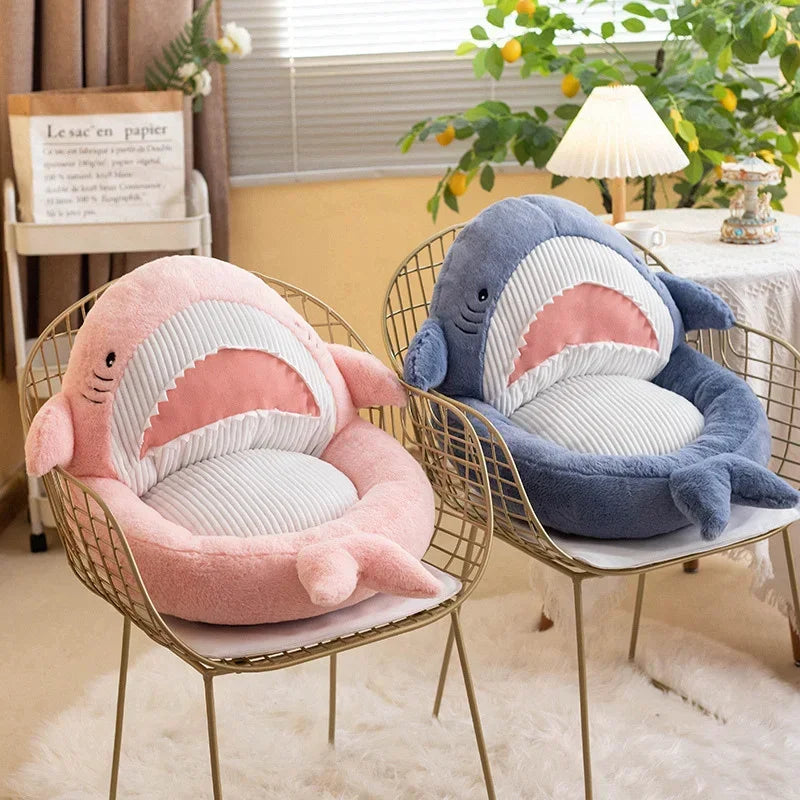 Two shark-shaped kawaii cushions on wire chairs in a room with plants and decor.
