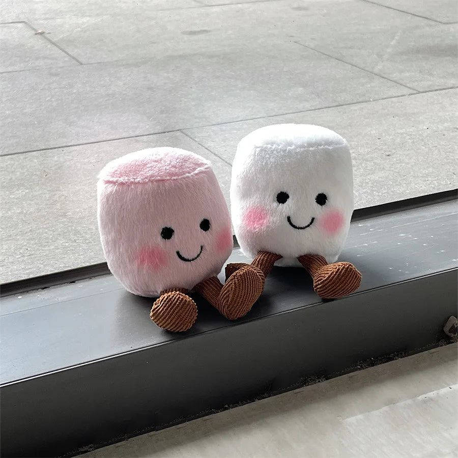 Two kawaii plush toys resembling marshmallows with smiling faces on a floor.
