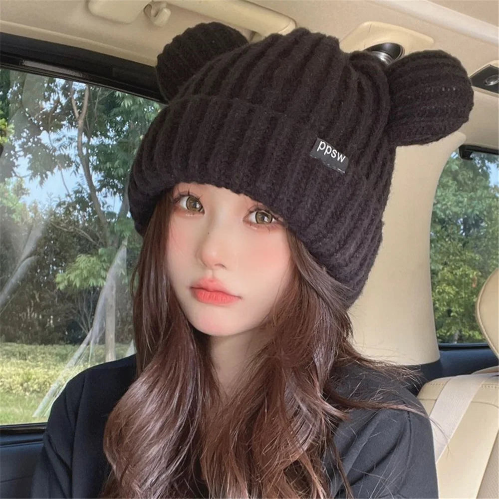 Person wearing a black knit Kawaii hat with bear ears inside a car