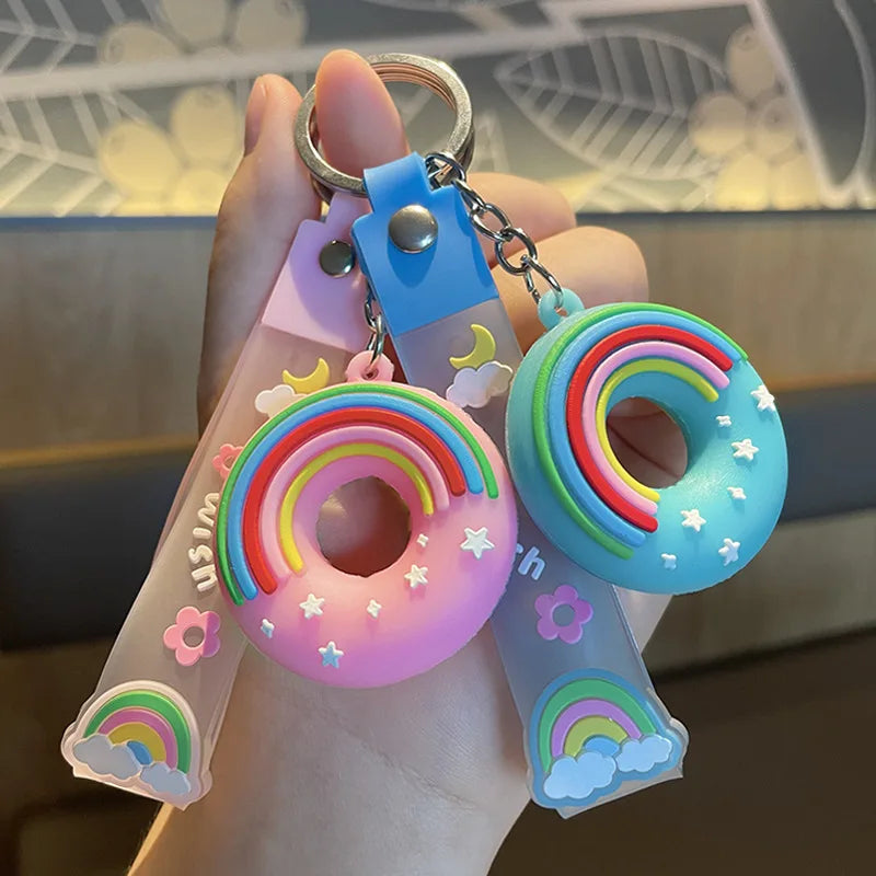 Colorful keychain with kawaii rainbow designs held in a hand against a blurred background