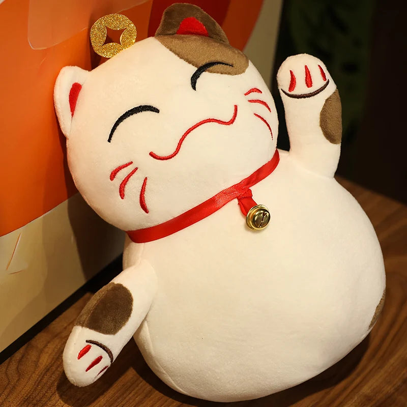 Kawaii plush toy of a maneki-neko cat with a red collar and gold bell on a wooden surface.
