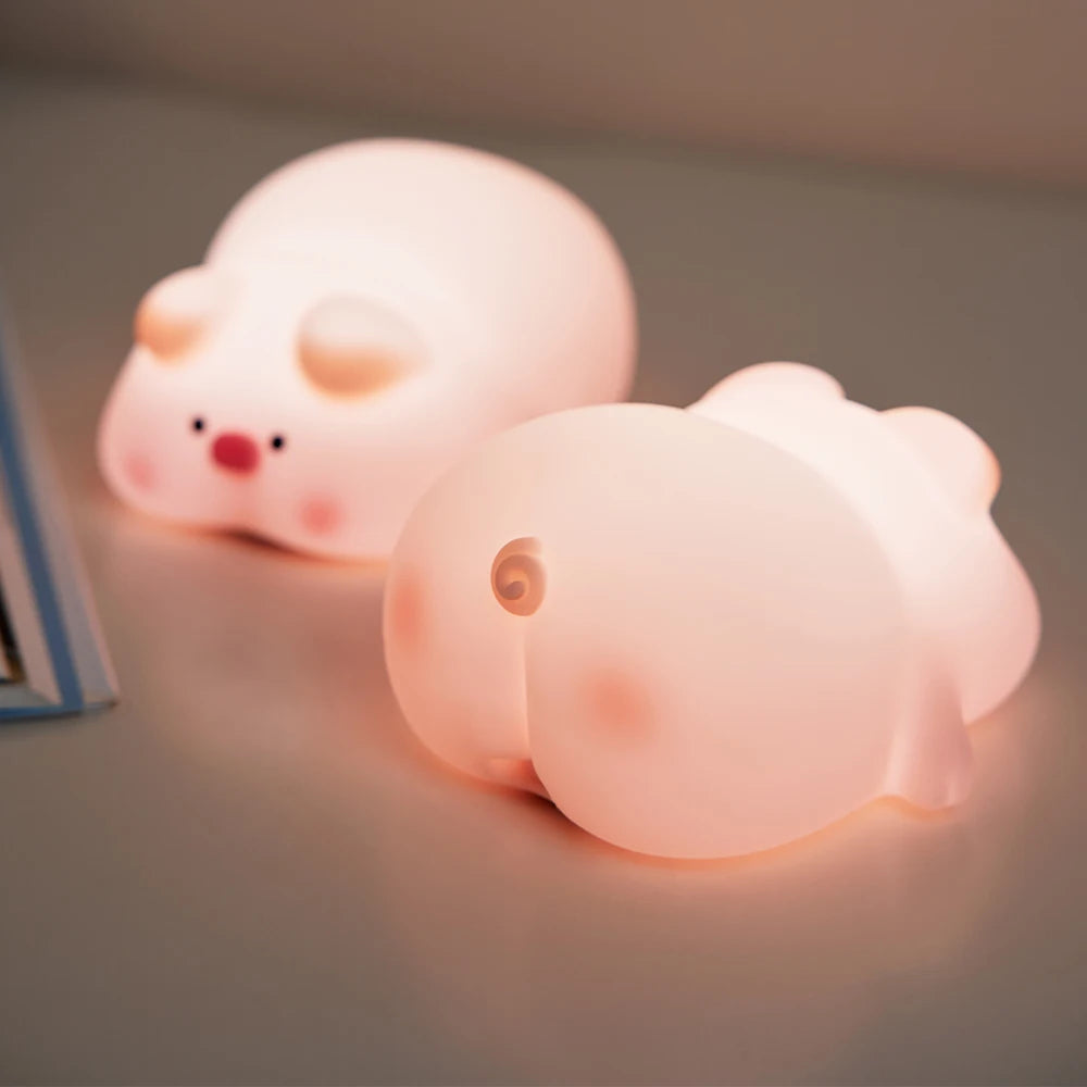 Two pink pig-shaped kawaii night lights on a neutral background