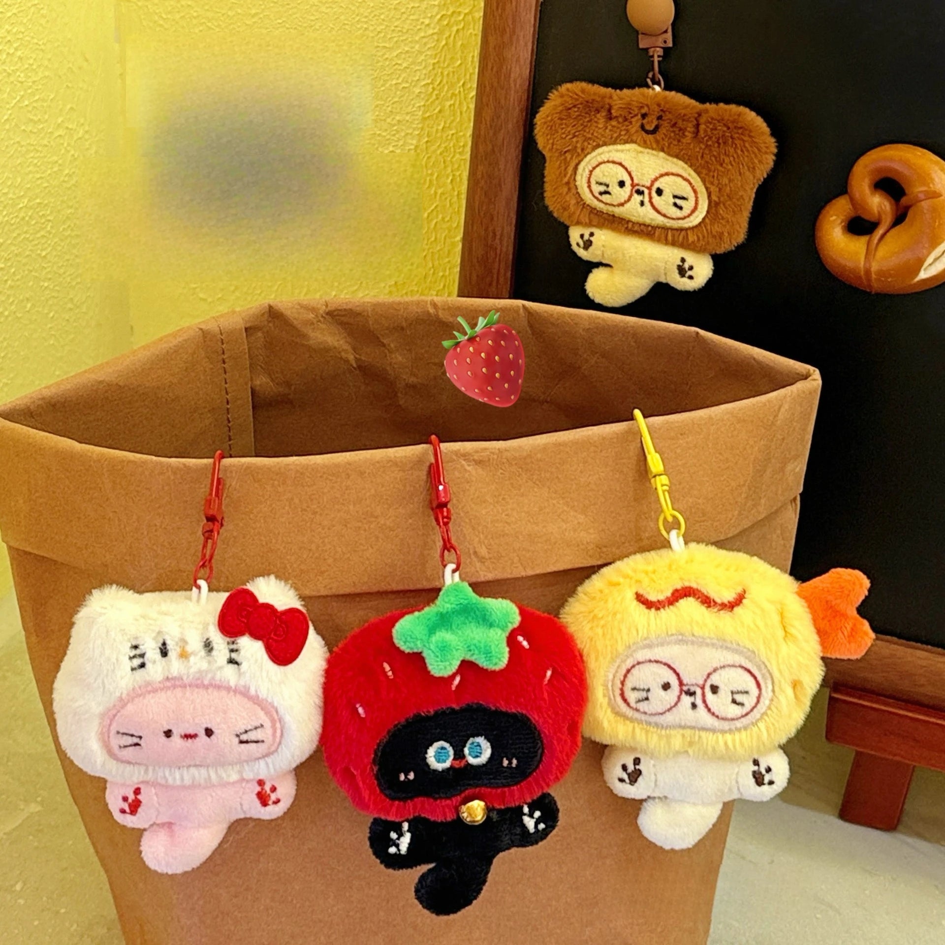 Kawaii plush keychains hanging from a brown bag against a yellow wall.