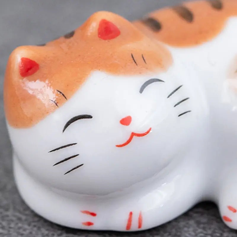 Ceramic kawaii cat figurine with a smiling face on a gray background