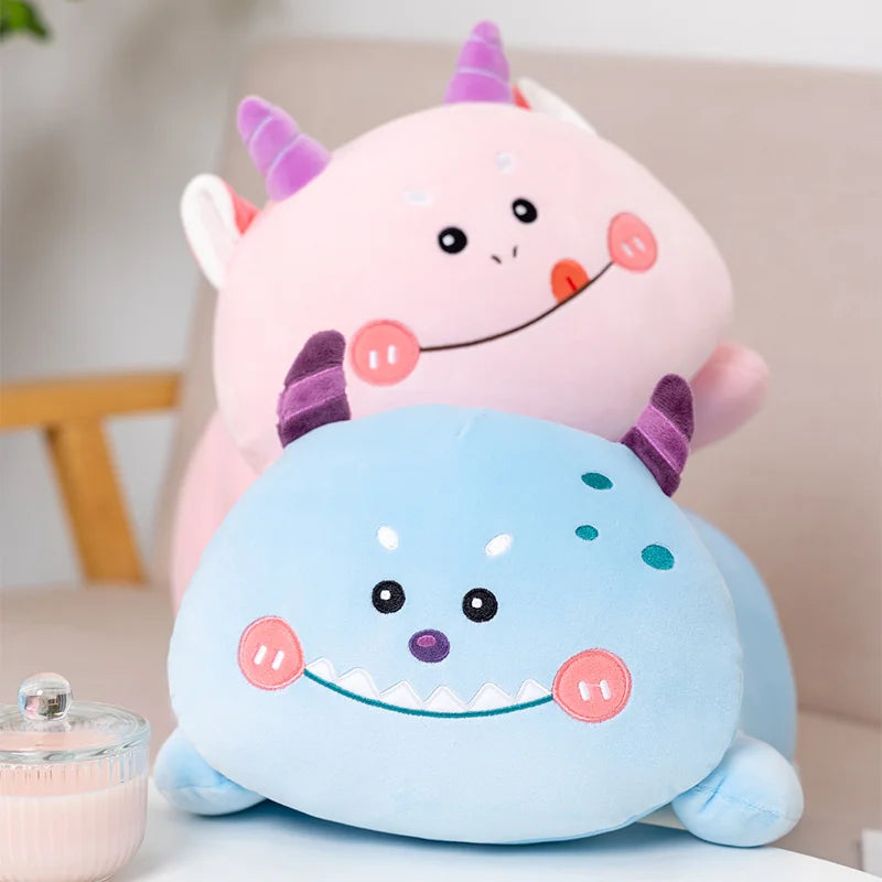 Two colorful kawaii plush toys, one pink and one blue, on a light surface with a blurred background.