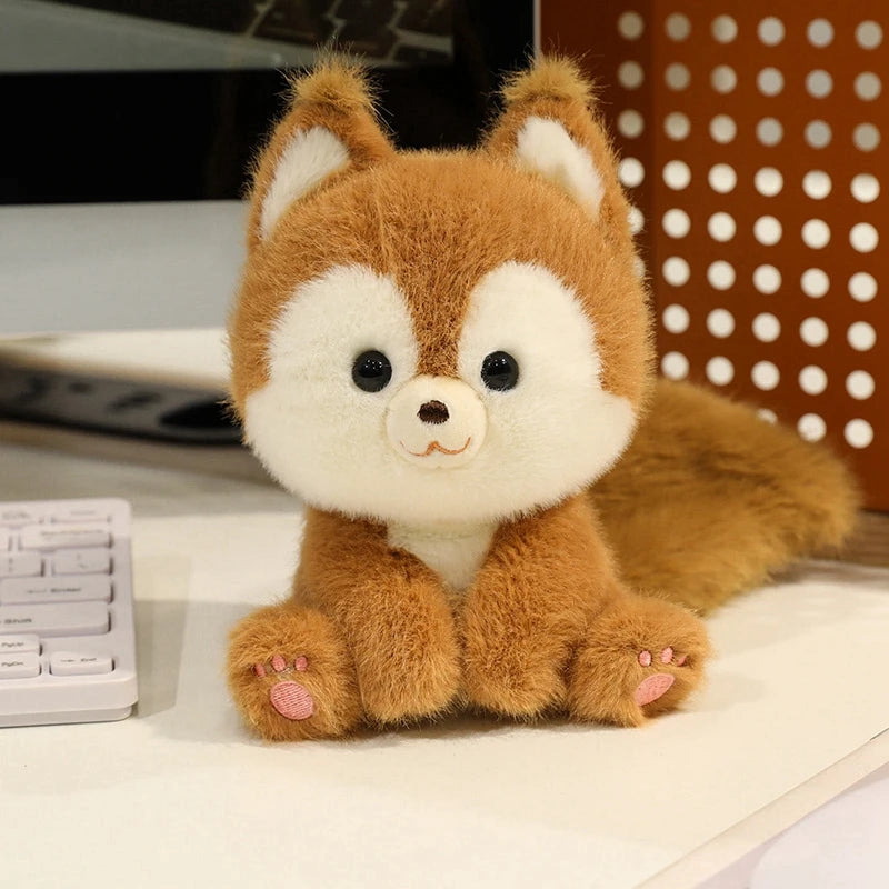 Plush kawaii toy fox sitting on a desk with a computer keyboard in the background