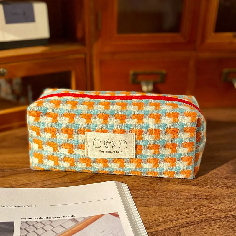 Colorful checkered kawaii pencil case on a wooden surface with a blurred background