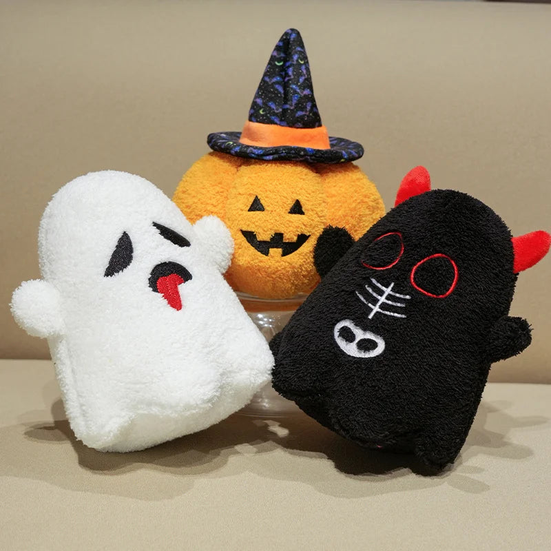 Three Halloween-themed plush kawaii toys: a ghost, a pumpkin, and a black cat on a beige background.