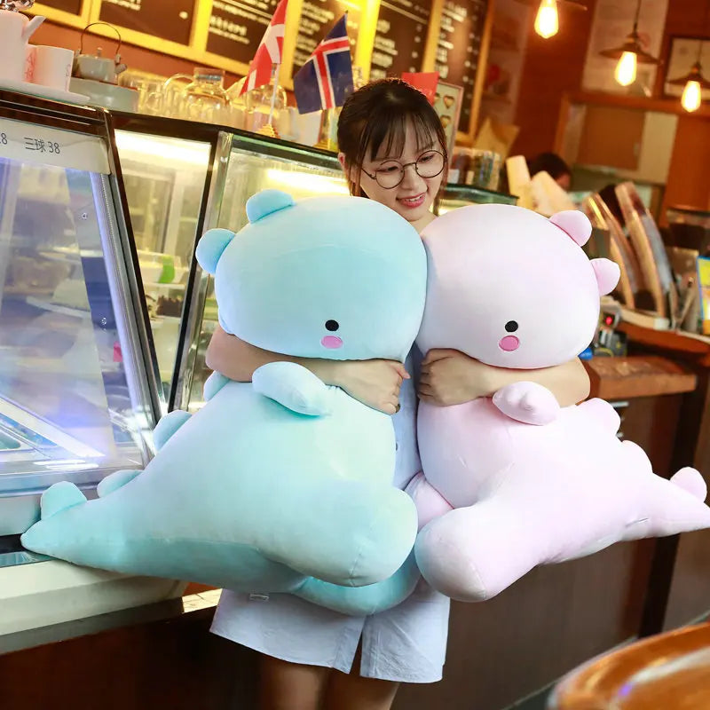 Person holding two large, soft, kawaii cartoonish animal plush toys in a restaurant setting.