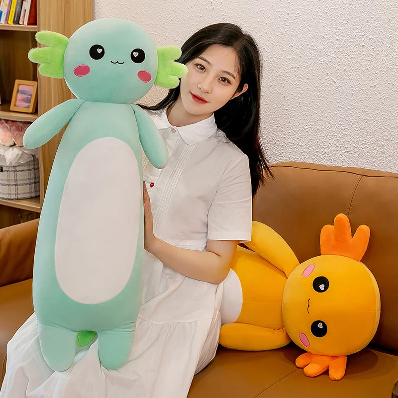 Woman holding a large green kawaii plush toy with a small orange plush toy on a couch.