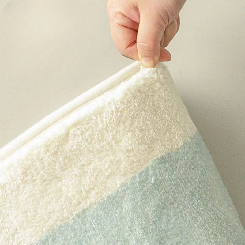 Hand holding a textured white and light blue kawaii rug against a plain background