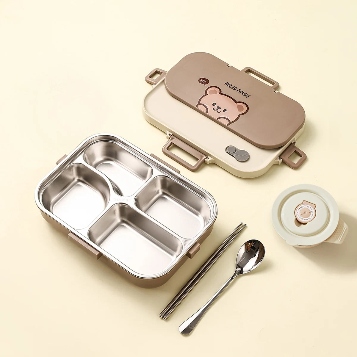 Children's kawaii lunch box set with compartments, lid, spoon, and chopsticks on a beige background