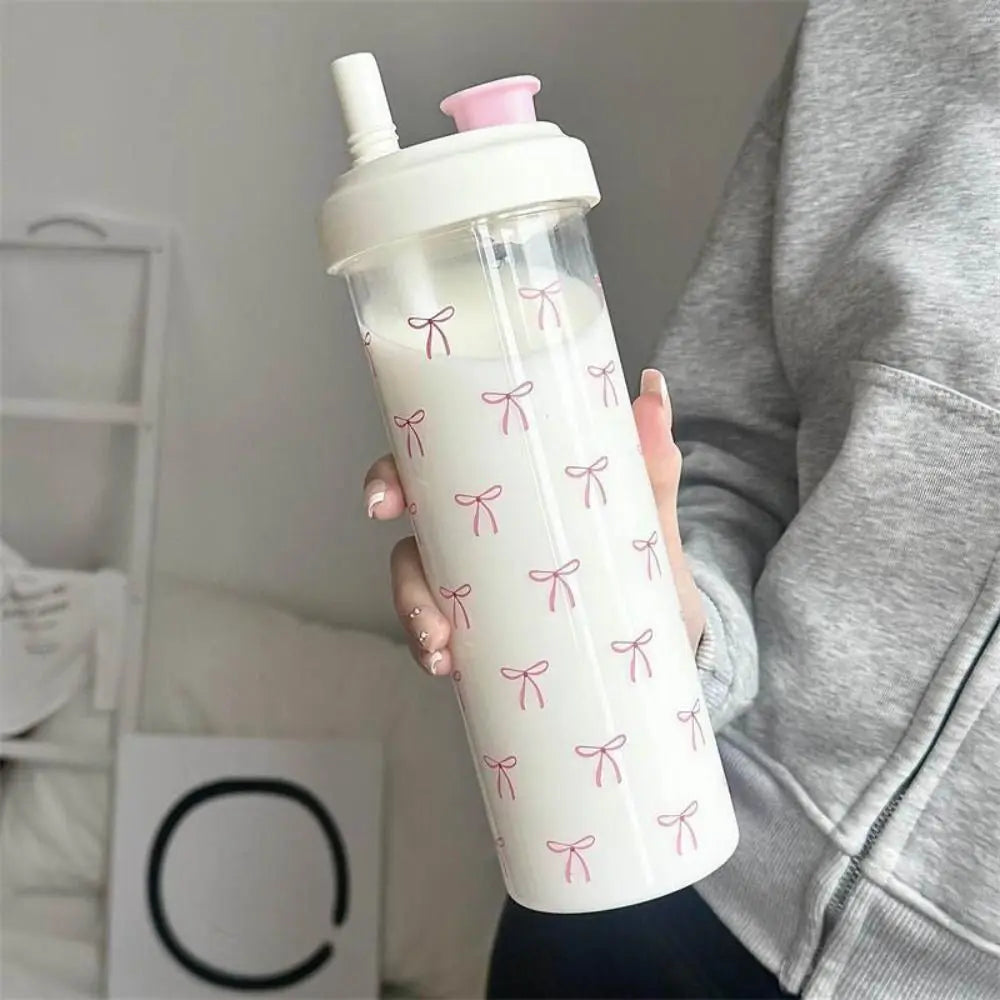 Person holding a clear tumbler with pink Kawaii bow designs and a pink lid.