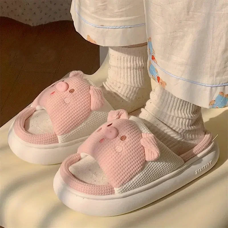 Pink cartoon character kawaii slippers worn with white socks and pajama pants.