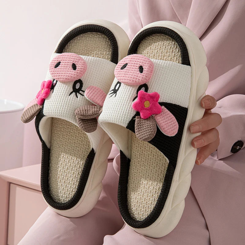Pair of white slippers with pink kawaii floral decorations held by a person on a pink background