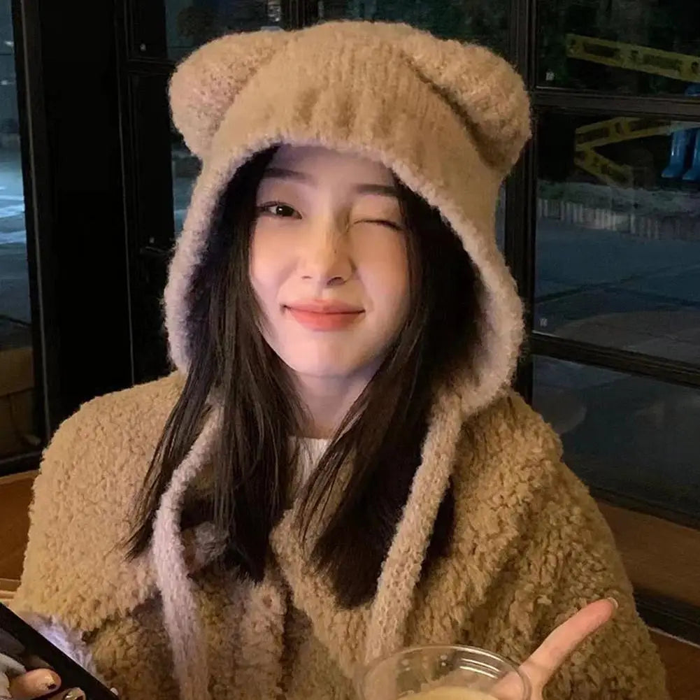 Person wearing a beige Kawaii bear-themed hat and coat, holding a glass.
