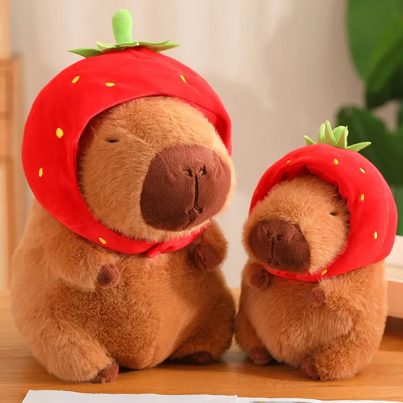 Two plush kawaii toys resembling bears wearing strawberry hats on a wooden surface.
