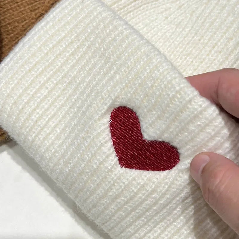 White fabric with a red heart Kawaii design held by a hand